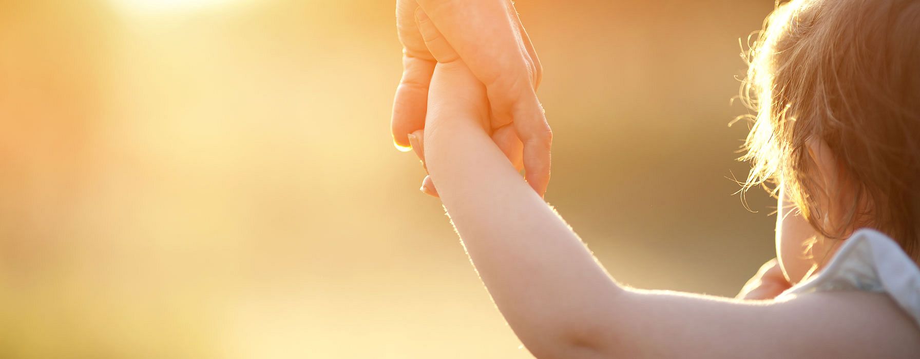 niño dándole la mano a una mujer con el atardecer de fondo