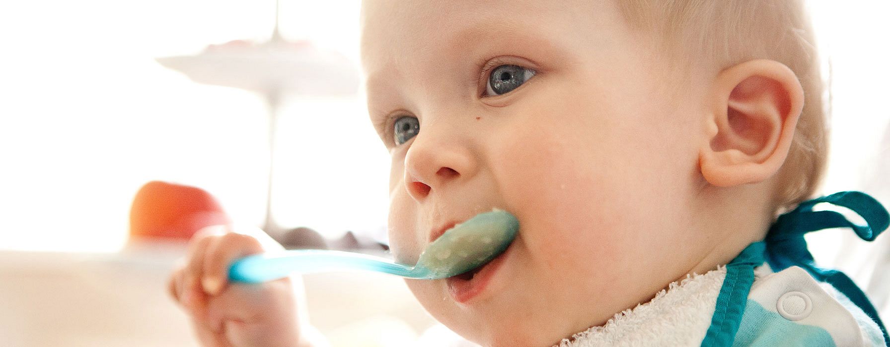 Bebé comiendo con una cuchara en la mano