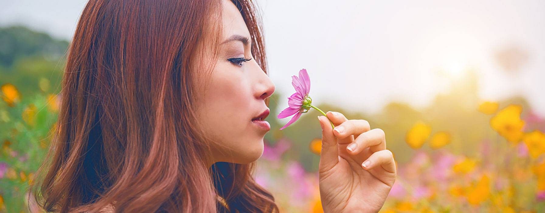 mujer en el campo oliendo una flor