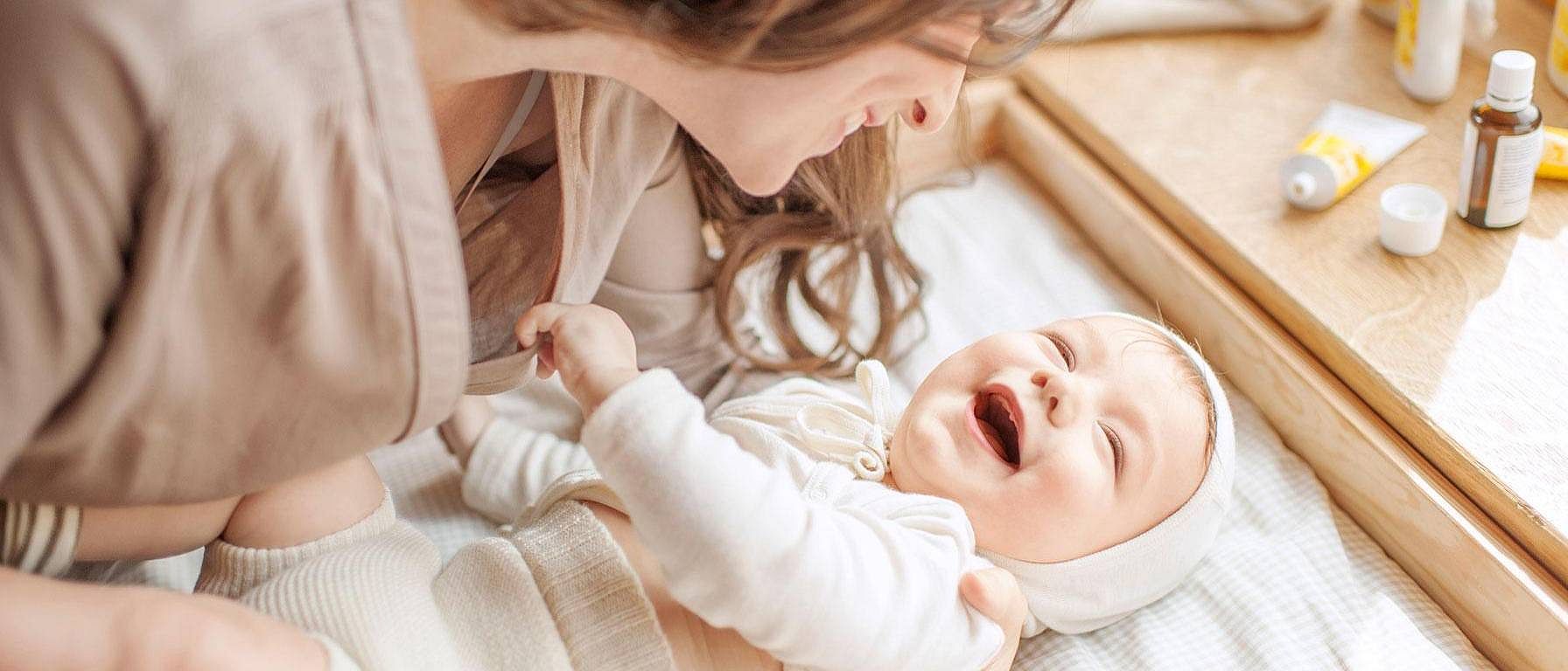 madre cambiando pañal a bebe sonriendo