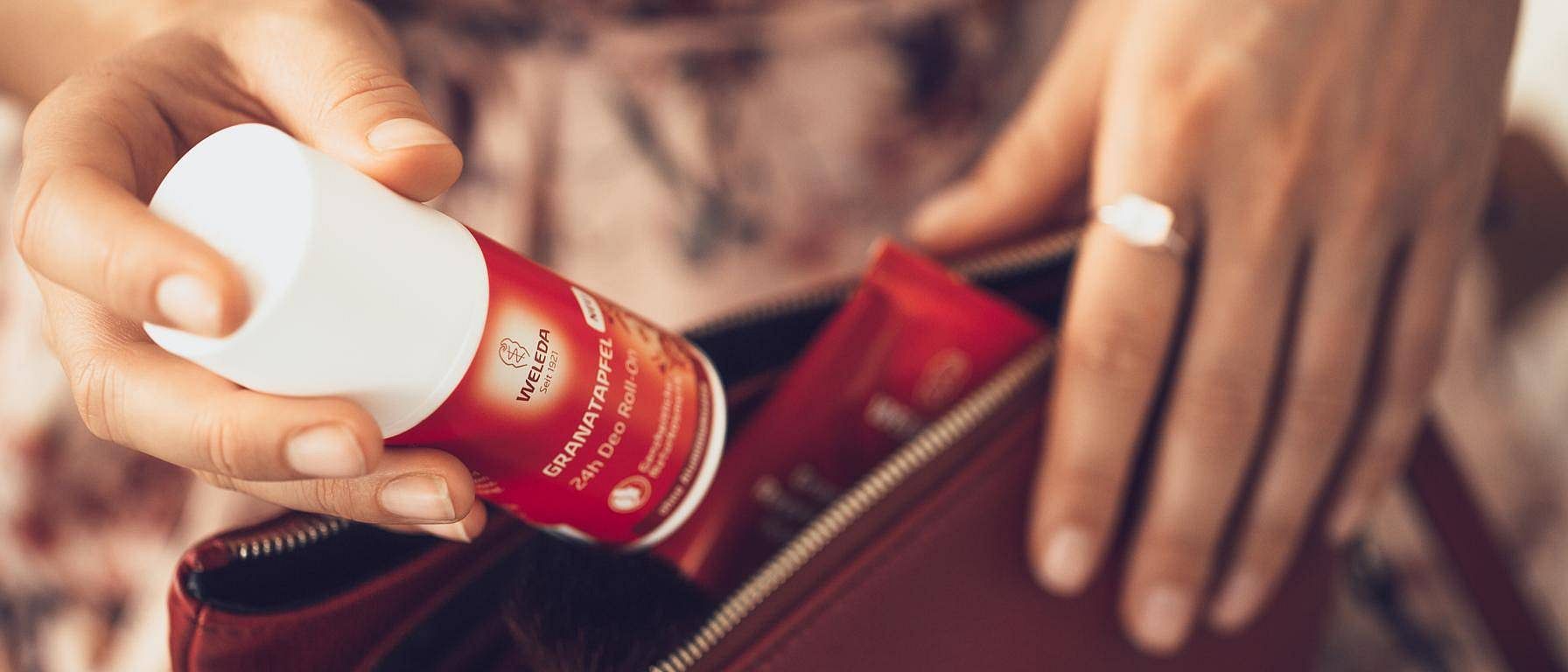 mano guardando el desodorante roll-on de granada de weleda en un bolso