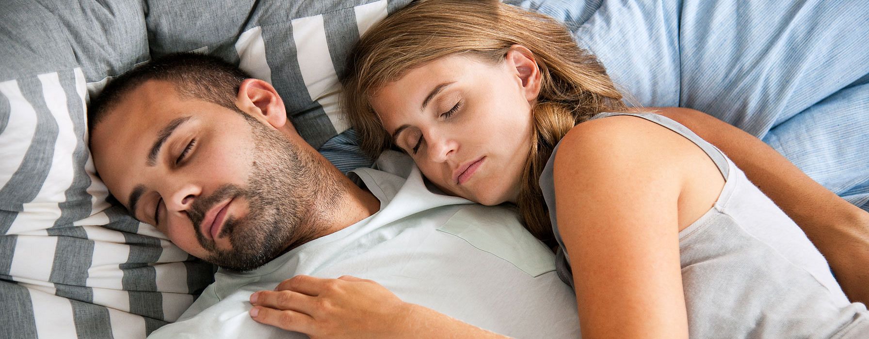 hombre y mujer tumbados en una cama durmiendo