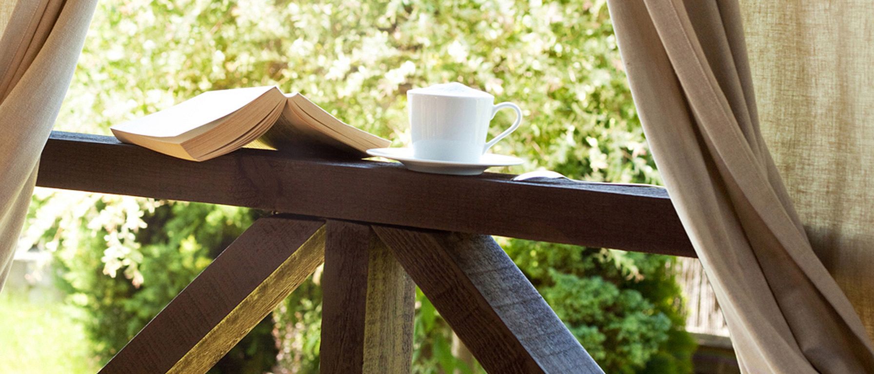 Libro, taza de té junto a una ventana que muestra la naturaleza exterior