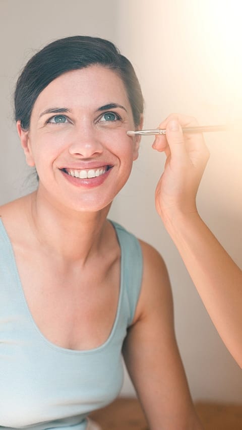 mujer maquillandose sonriendo