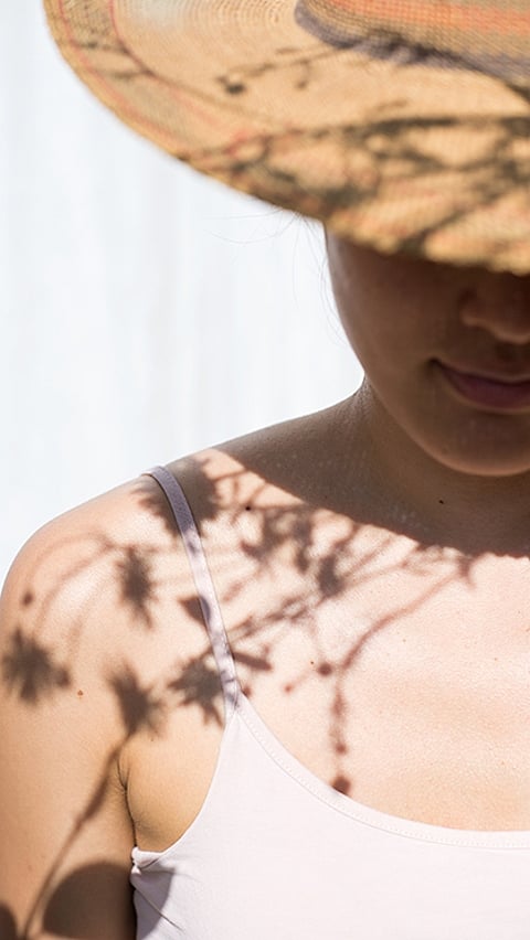 Mujer en un sombrero con un patrón de sombra de una flor.
