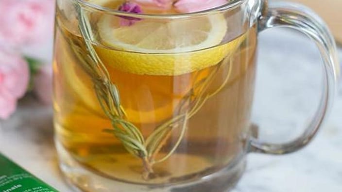 infusion en vaso con rodaja de limon y petalos