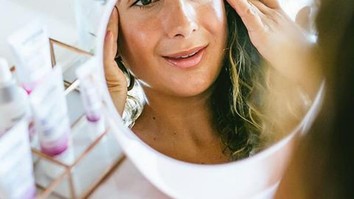 reflejo de una mujer en un espejo mirandose la cara