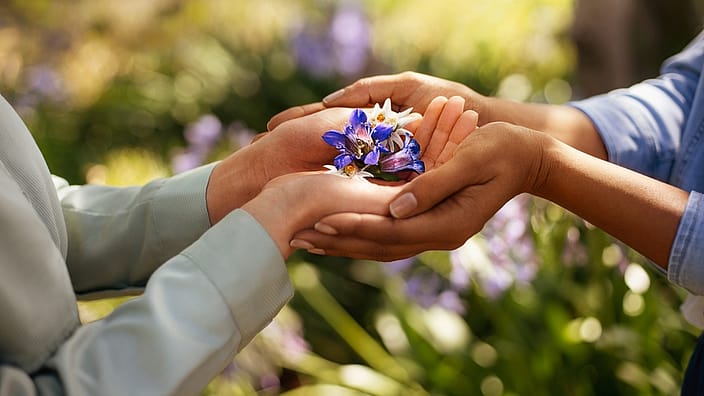 four hands holding flowers together
