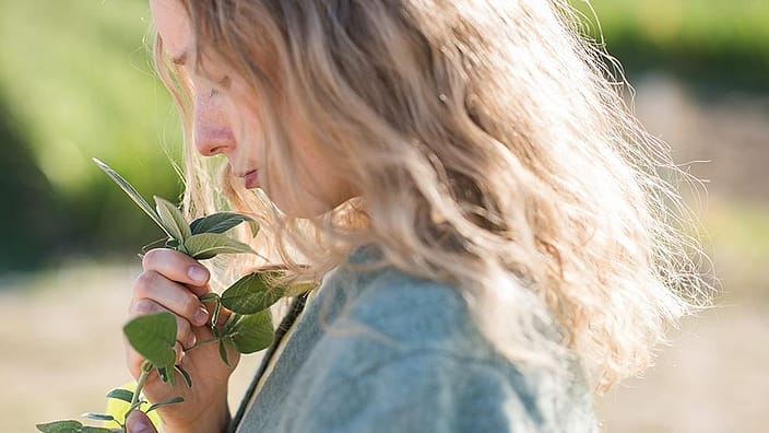 mujer oliendo flores