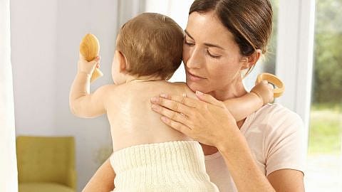 mujer abrazando al bebé que tiene en brazos