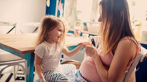 mujer embaraza con su hija sentada en el regazo