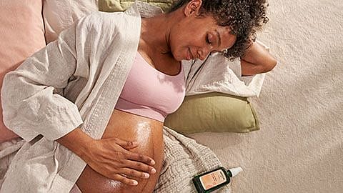 mujer embarazada tumbada, mirandose la tripa y sonriendo