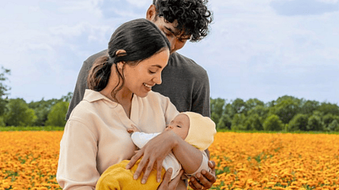 pareja con bebe en brazos en campo de calendula
