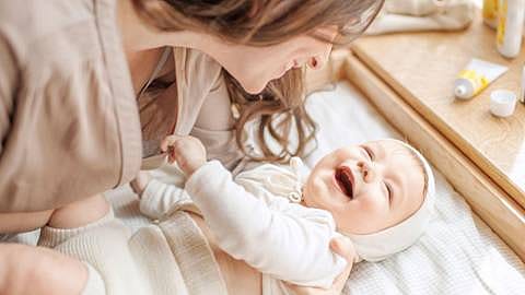 madre cambiando pañal a bebe sonriendo