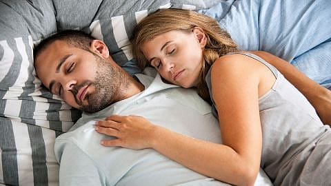hombre y mujer tumbados en una cama durmiendo