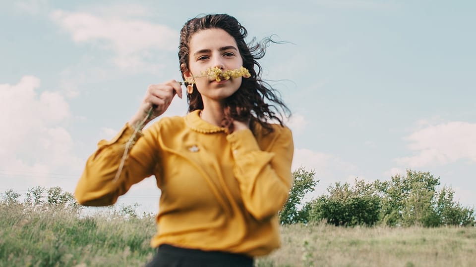 Mujer joven oliendo una flor