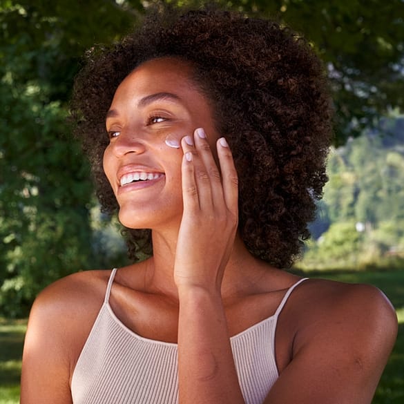 mujer aplicando la crema de día de skin food en el rostro mientras sonrie