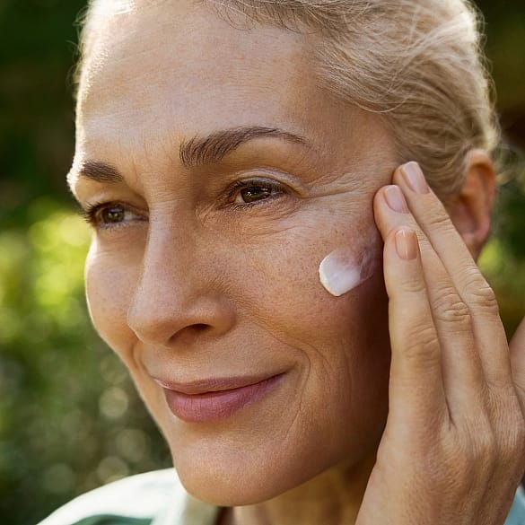 Mujer aplicandose la crema de dia redensificante de genciana azul y edelweis