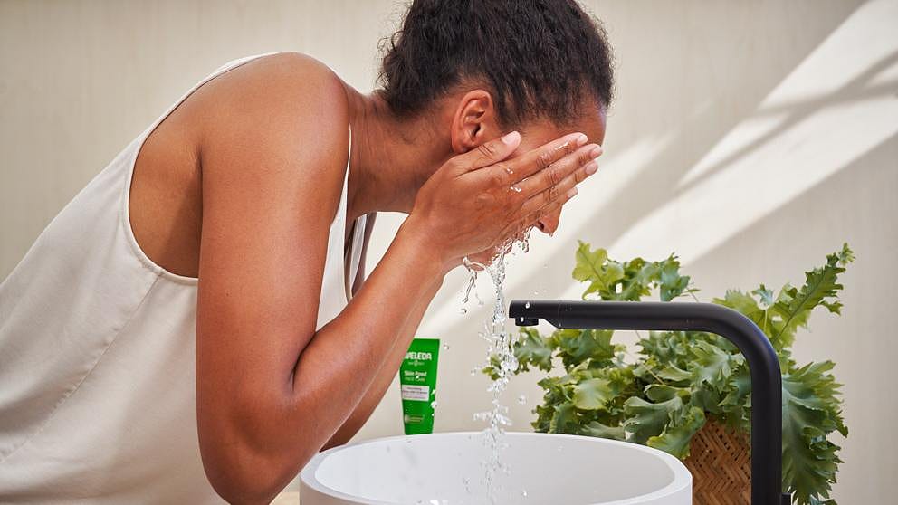 mujer enjuagandose la cara en el baño tras aplicarse el bálsamo limpiador de skin food