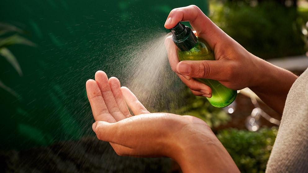 mano pulverizando aceite seco spray