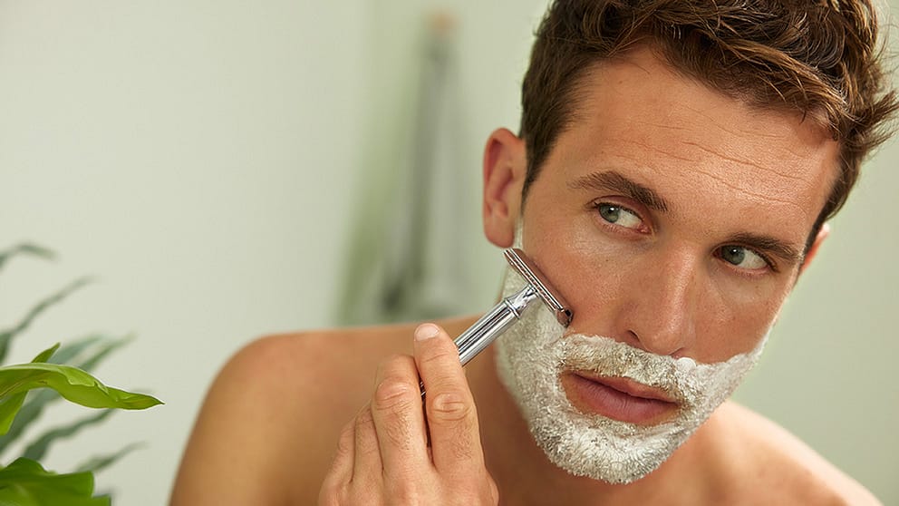 hombre afeitandose con crema de afeitar y cuchilla